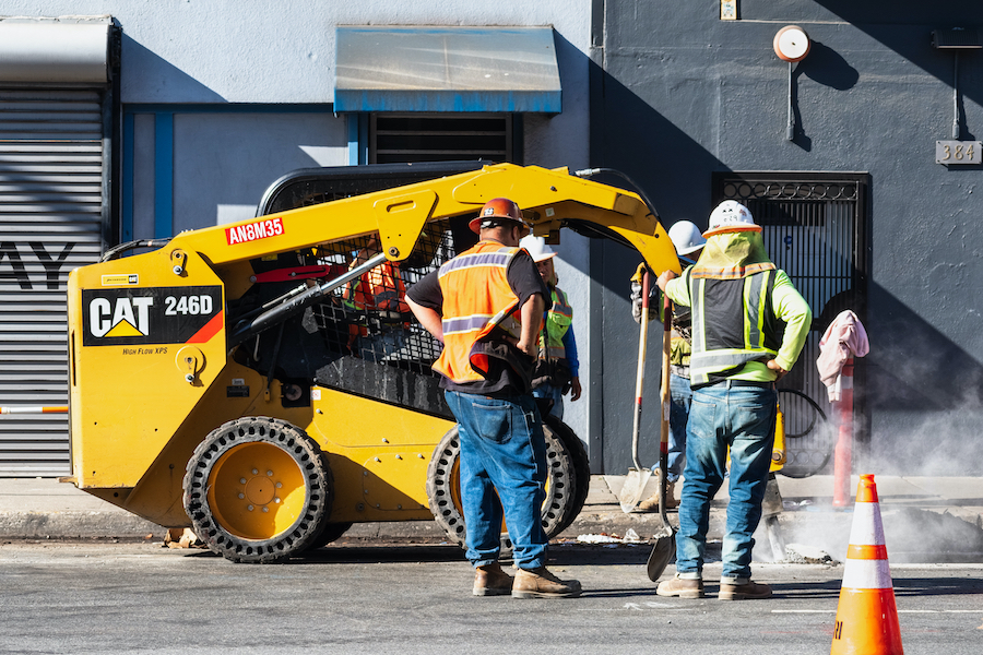 Contractor Inspecting Skid Steer Attachment Contractor Inspecting Skid Steer Attachment