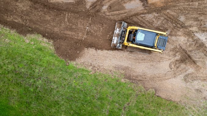 Drone,Photo,Of,Skid,Steer,Clearing,And,Leveling,Land A skid steer is one of the most versatile machines in landscaping, capable of grading soil, moving materials, and clearing debris with precision. Its compact size and interchangeable attachments make it ideal for working in tight residential or commercial spaces.