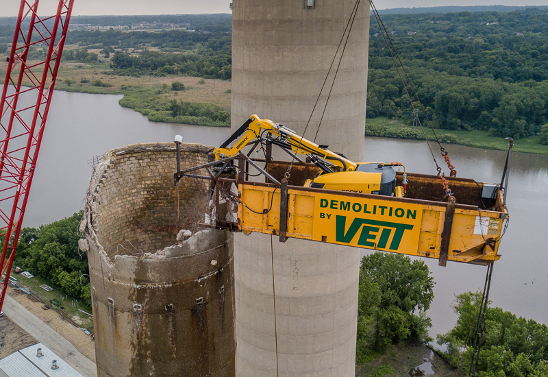 High-elevation demolitions use suspended platforms and remote-operated machinery to keep workers out of danger zones. Safety harnesses, load sensors, and controlled debris removal ensure stability throughout the process. Photo Credit: Veit