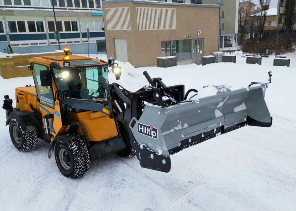 Skid steers equipped with compatible plow attachments deliver exceptional control in tight spaces. They are often used for heavy storms because they can push dense snow where larger trucks struggle. Photo Credit: Hilltip