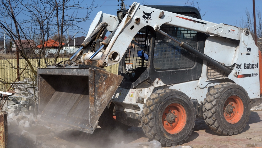 Skid steer loaders are designed for tight spaces and firm surfaces, using differential steering to pivot within their own footprint. This maneuverability makes them popular for urban construction, demolition cleanup, and material handling tasks.