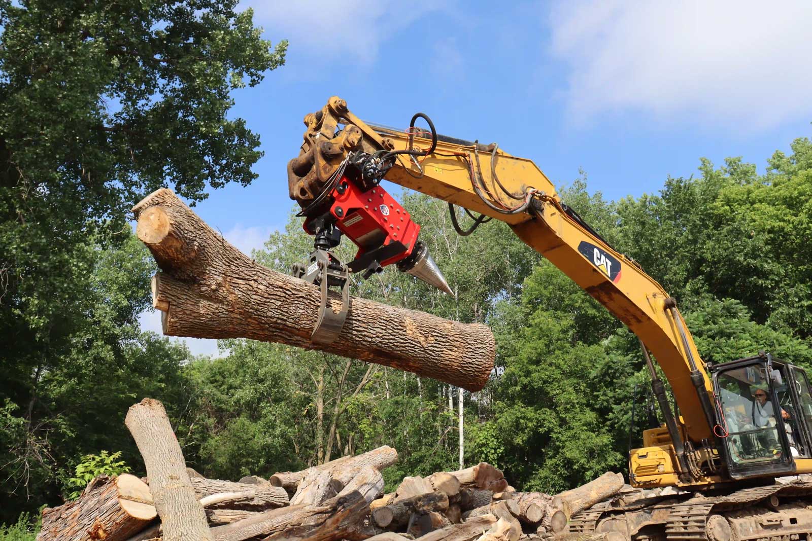 The HF-800 Cone Screw Splitter with Grapple splits large logs and also lets the operator move, load, and position them. The 52-inch rotating grapple helps one machine handle splitting and log placement without changing attachments. Photo Credit: U.S. Pride Products