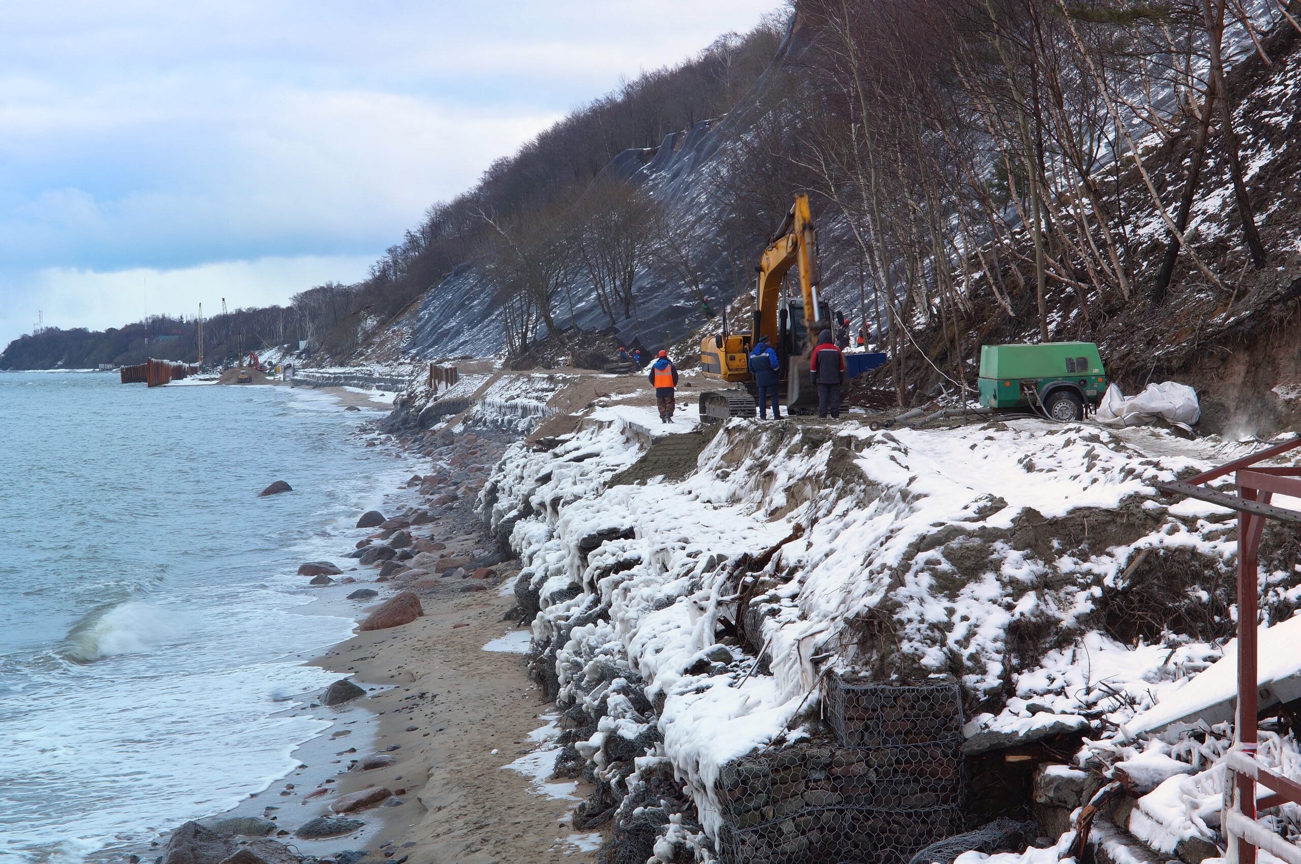 Yellow excavator working coastal shore fortification jobsite