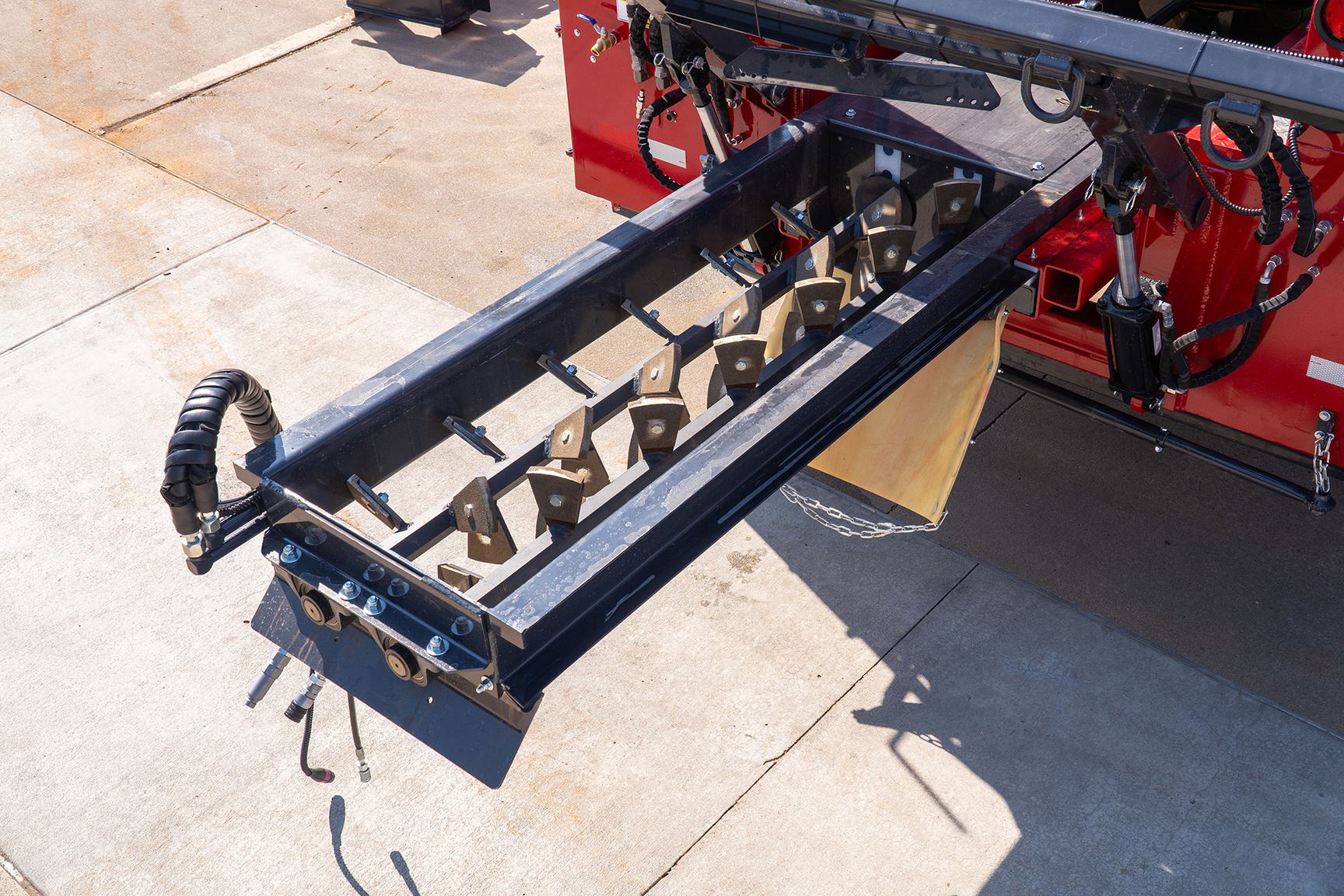 Close-up of pugmill mixing paddles extended on a slurry seal and microsurfacing paver for aggregate and emulsion blending