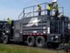Crew operating a continuous slurry seal and microsurfacing paver applying a fresh preservation mat on a rural two-lane road