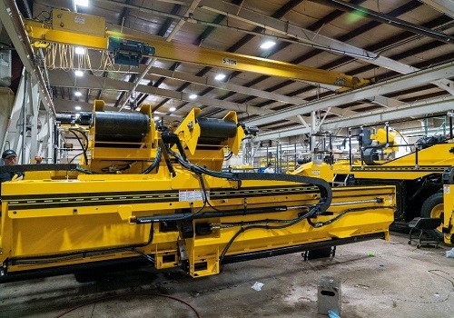 Yellow Etnyre chip spreader components in assembly with hydraulic lines and rollers