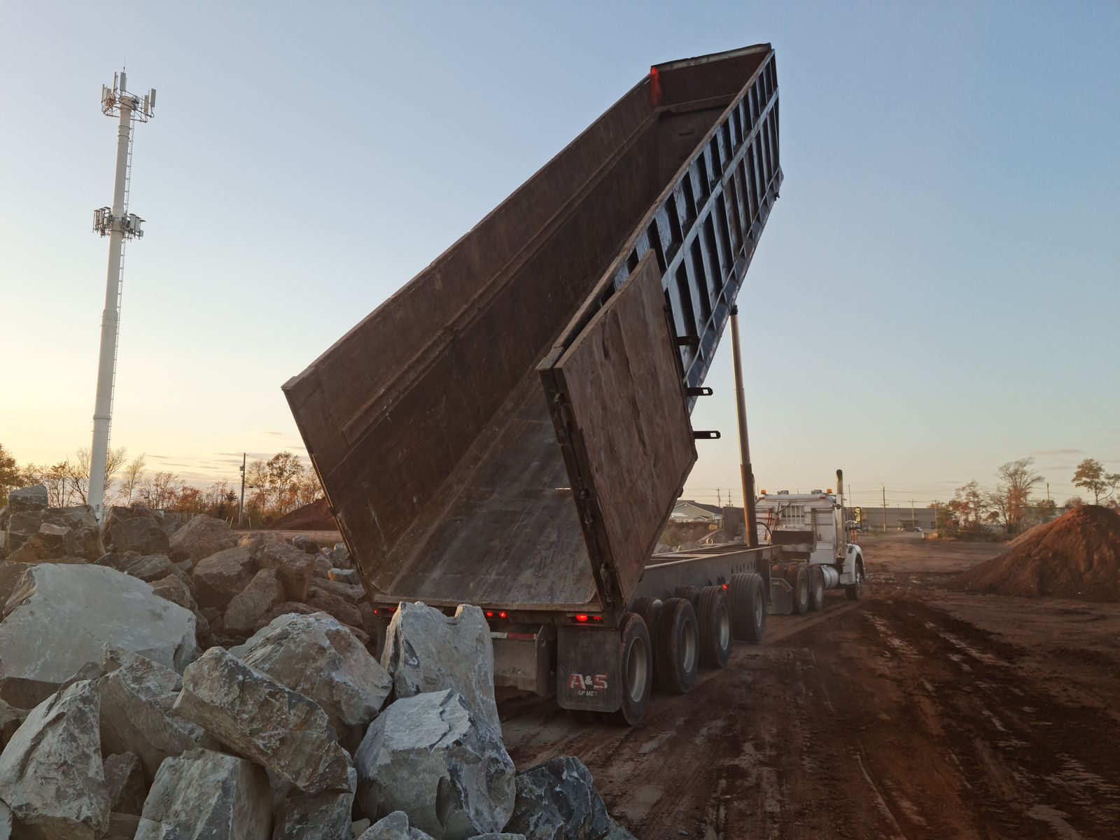End dump truck tipping stone and aggregate on a construction site