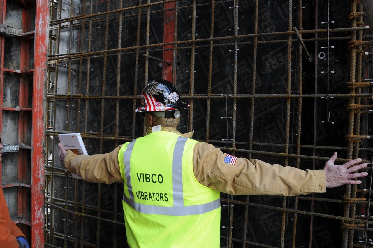 Worker in VIBCO Vibrators vest standing before dense rebar and PERI form panels