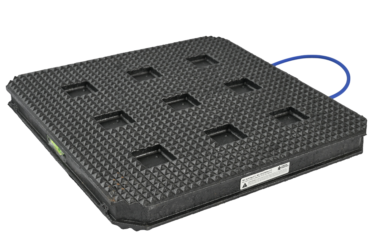 Black square modular outrigger pad with waffle texture, blue handle, side label, and built-in bubble level