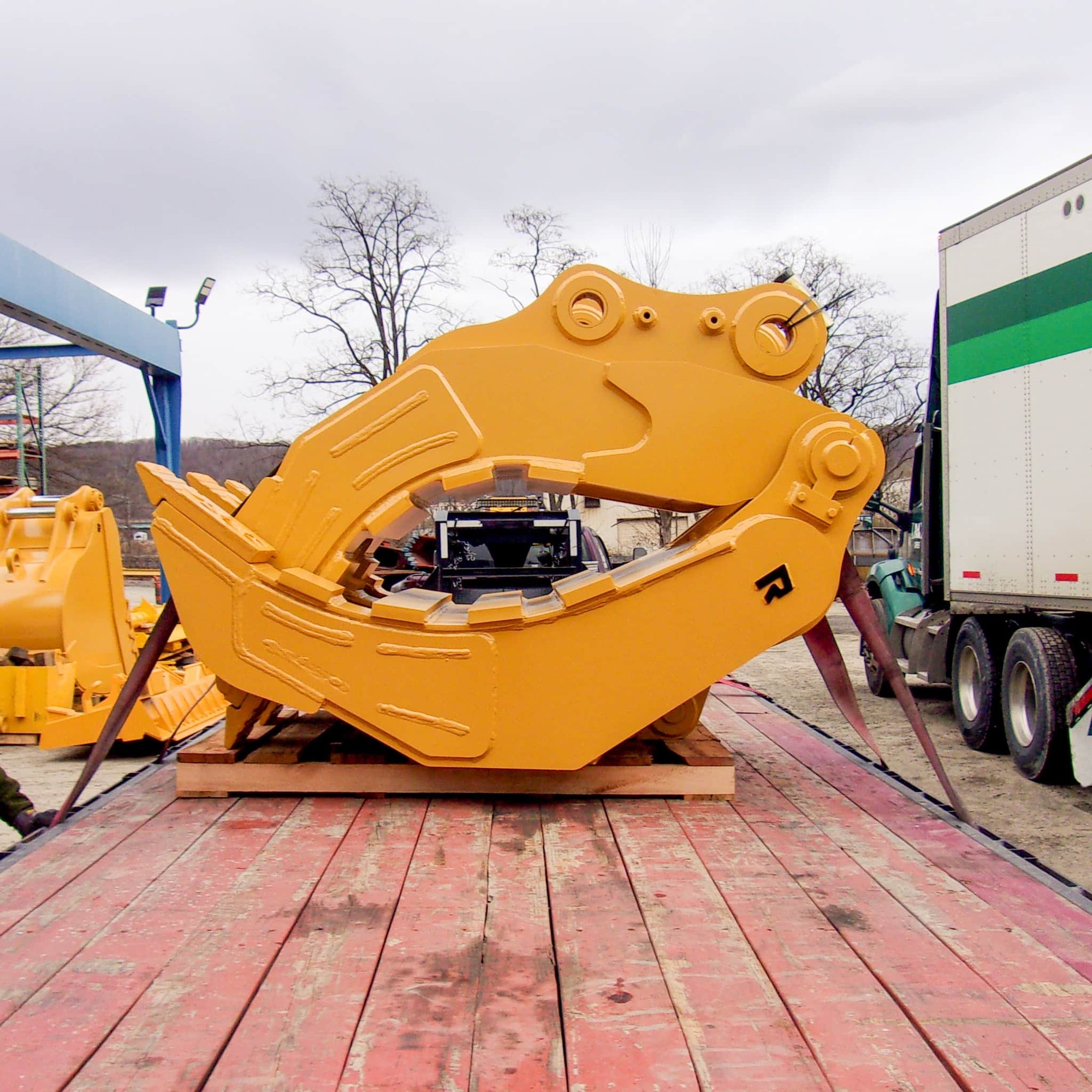 Yellow Rockland H23 extreme-duty excavator grapple strapped on a flatbed trailer