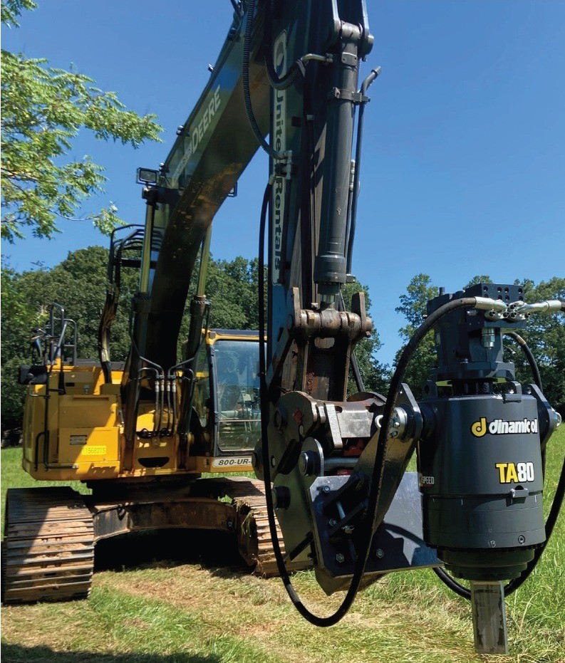 John Deere excavator raising a gray Dinamic Oil TA80 high-torque auger drive in a field