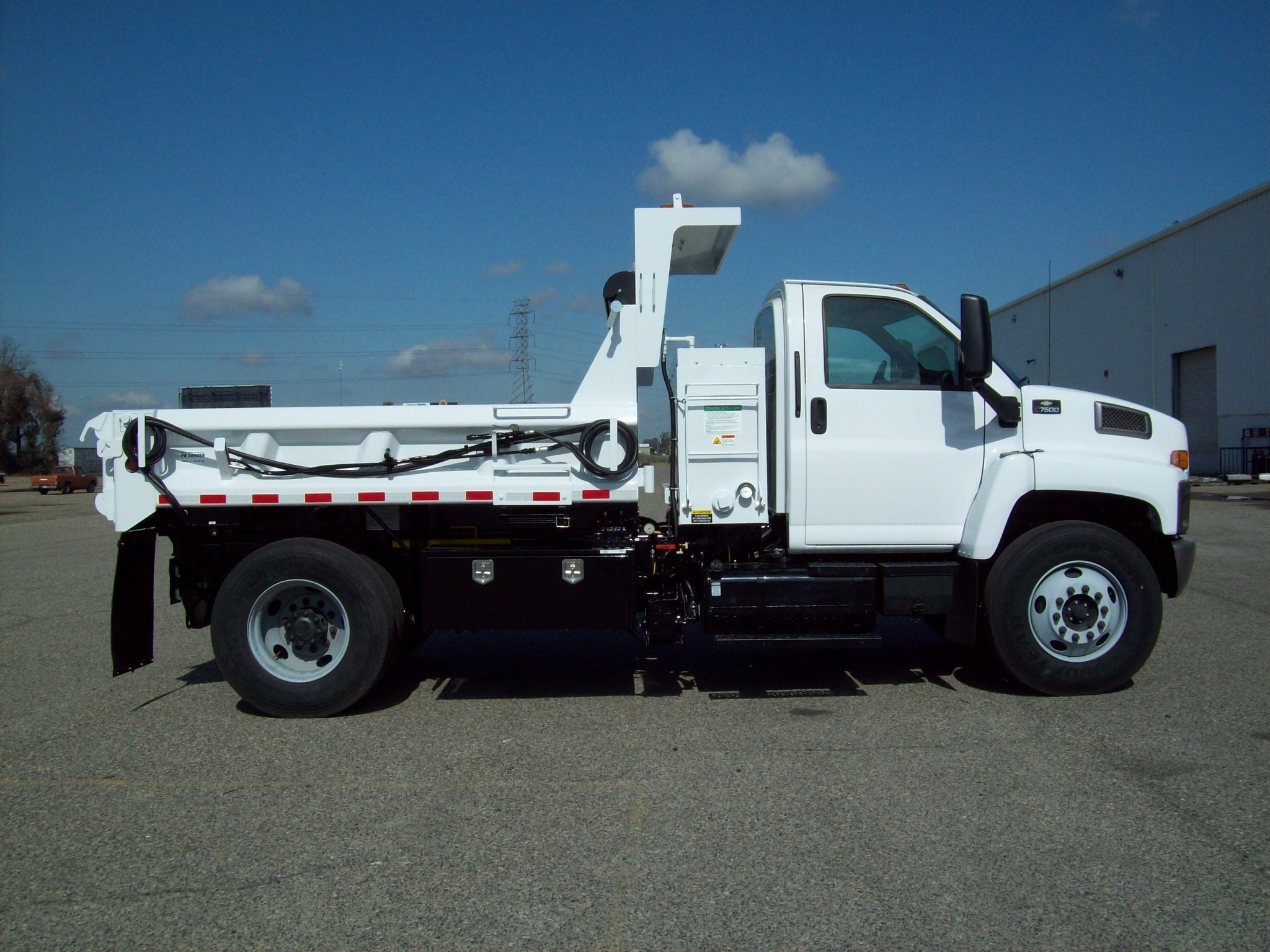White Chevrolet patch truck with PB Loader emulsion system housing and coiled hoses