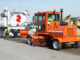 Construction broom sweeping milled asphalt behind a cold planer