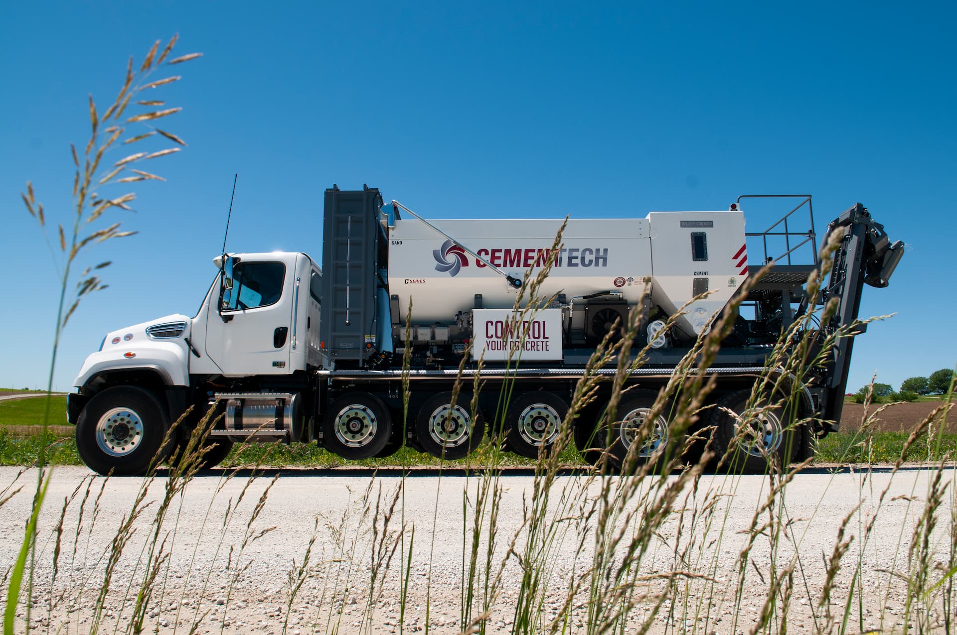 White Cemen Tech C-Series volumetric mixer truck parked on a gravel road under blue sky