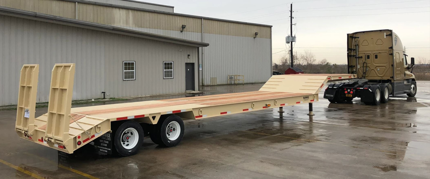 Tan Choice Trailer drop-deck with rear ramps hitched to a gold semi tractor