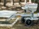 Gray MudMixer continuous concrete mixer discharging wet concrete into a wood-formed residential slab with rebar over sand outdoors