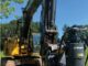 Dinamic Oil TA80 hydraulic auger drive mounted on yellow John Deere excavator in a grassy field