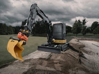 Compact excavator with orange tiltrotator and yellow AMI grading bucket working a sand-lined trench
