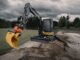 Compact excavator with orange tiltrotator and yellow AMI grading bucket working a sand-lined trench