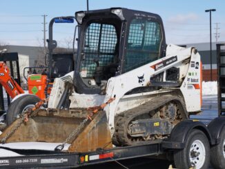 Bobcat compact track loader secured on a tandem-axle equipment trailer