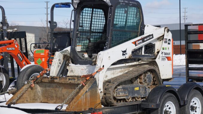Bobcat compact track loader secured on a tandem-axle equipment trailer