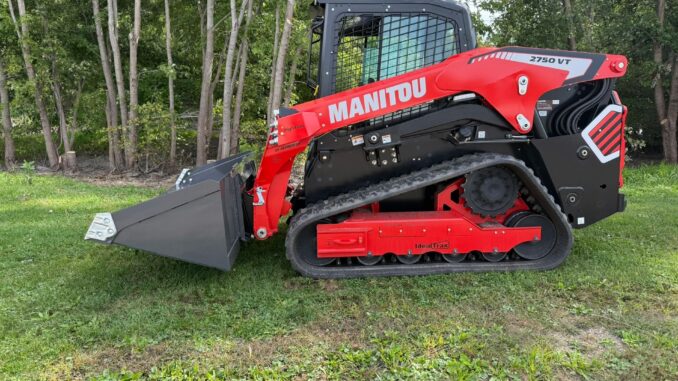 Red compact track loader with grey dirt bucket on grass illustrating ROC-matched bucket sizing