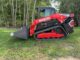 Red compact track loader with grey dirt bucket on grass illustrating ROC-matched bucket sizing