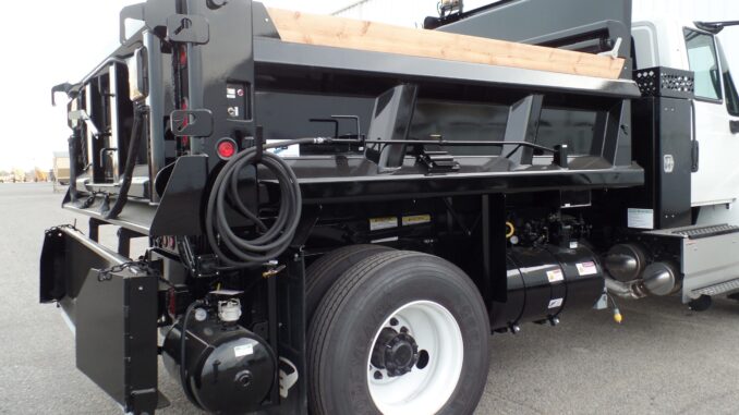 Black PB Loader asphalt patching truck showing rear emulsion tank, hose, and controls