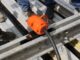 Orange external pneumatic form vibrator clamped between modular aluminum form rails on a precast pour