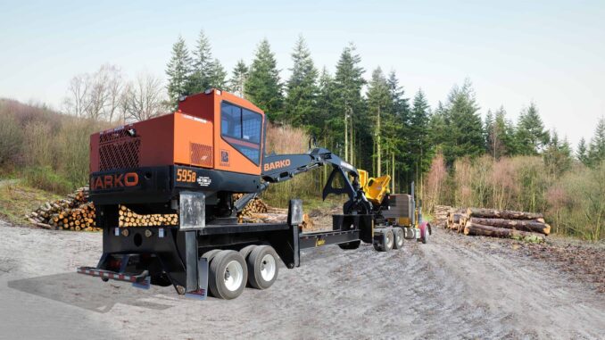 Orange Barko knuckle-boom log loader mounted on a multi-axle carrier trailer at a timber landing