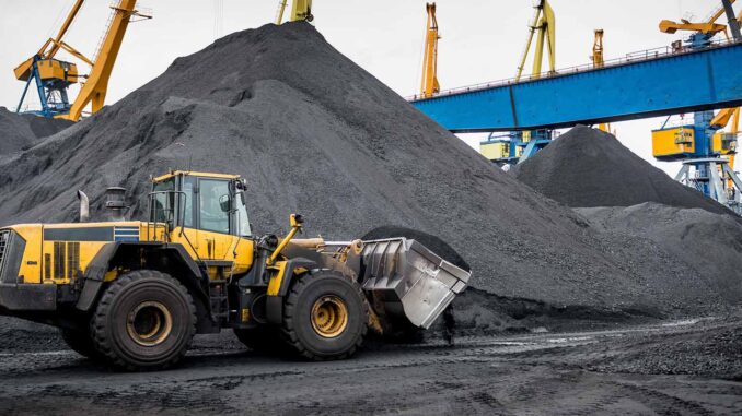 Large OTR tires on yellow rigid-frame haul trucks staged for earthmoving duty