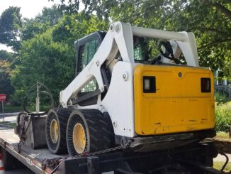 Skid steer loader chained on a tag trailer deck ready for transport