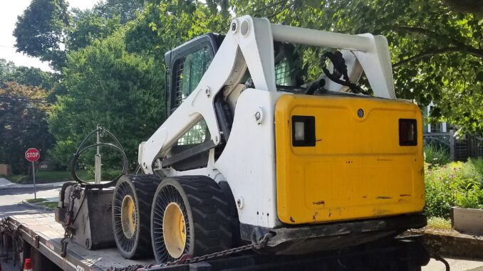 Skid steer loader chained on a tag trailer deck ready for transport