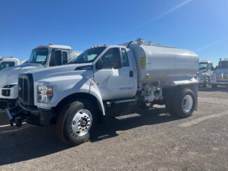 White Ford F-750 with Valew cylindrical water tank body parked on a gravel lot