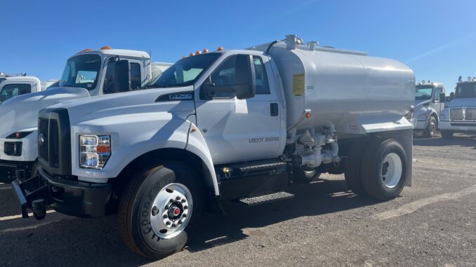White Ford F-750 with Valew cylindrical water tank body parked on a gravel lot