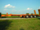 Orange Hudson equipment trailer with dual rear loading ramps on a rural driveway